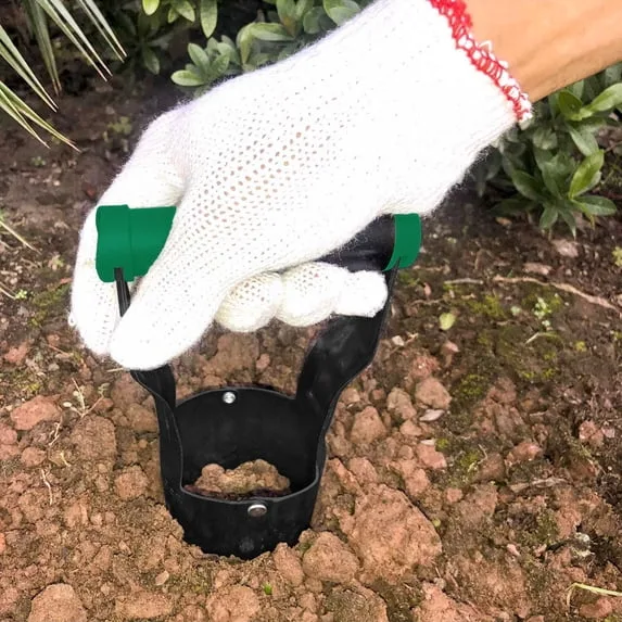 A handheld bulb planter being pushed into soil.
