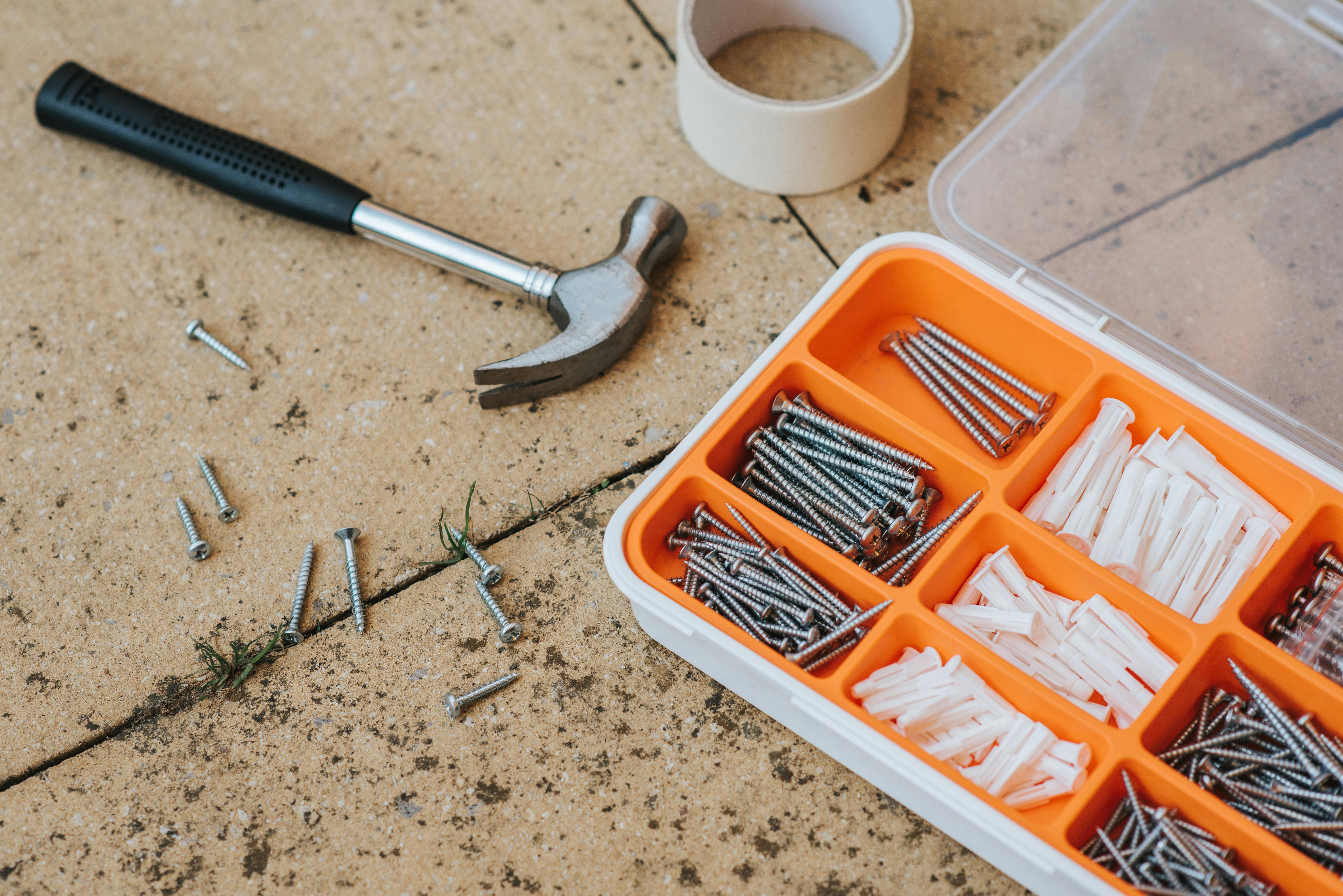 Claw hammer and screw set on a neutral background.