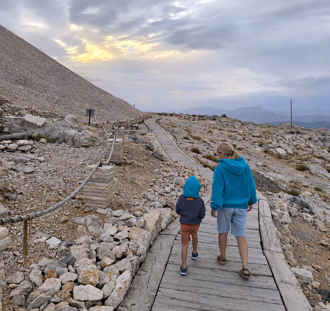 Woman and child wearing SIDURO fleece hoodies on a wooden path through a rocky mountain landscape