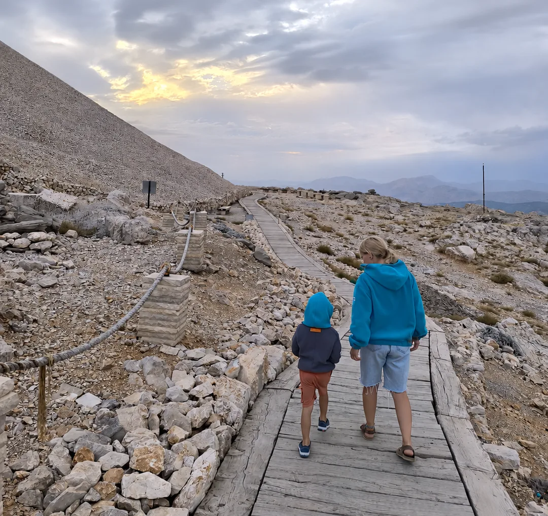 Woman and child wearing SIDURO fleece hoodies on a wooden path through a rocky mountain landscape