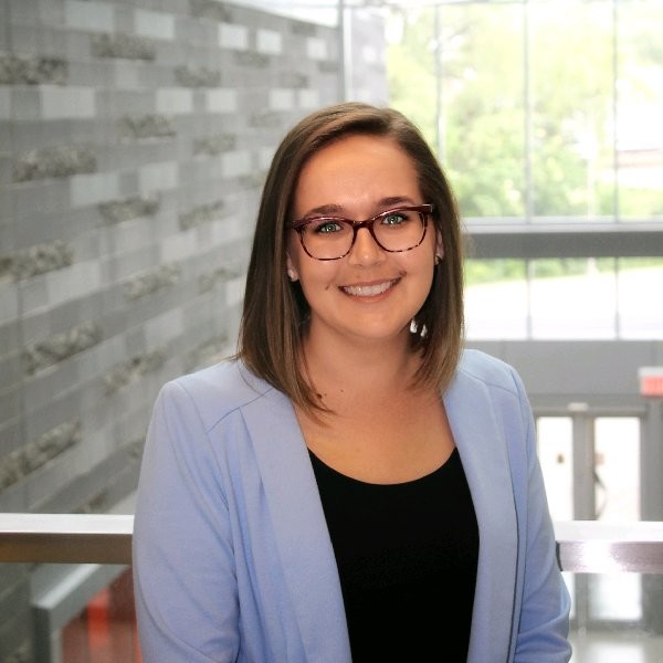 A woman in a blazer smiles at the camera.