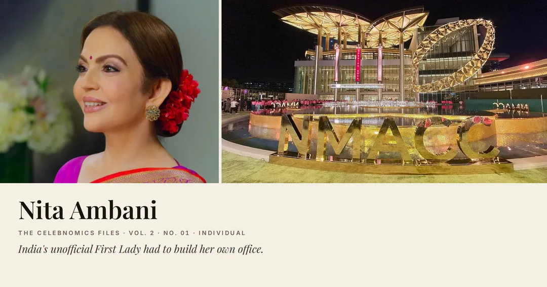 The Nita Mukesh Ambani Cultural Centre lit at night, its NMACC sign in gold beside a reflecting pool, next to a portrait of Nita Ambani in a pink sari.