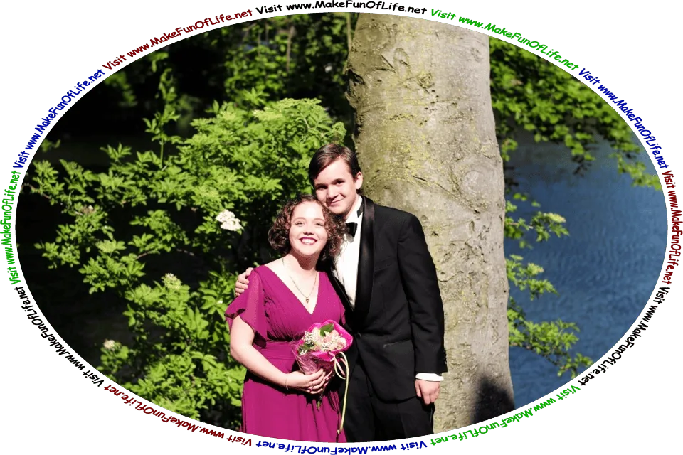 Picture of a happy smiling couple on their wedding day standing under a green leafy Tree next to a calm blue lake, and the words, ‘Visit www.MakeFunOfLife.net.’