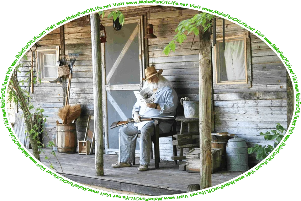 Picture of a man with a beard and shoulder-length white hair sitting on a chair on the porch of a small rustic wooden house in a woods, reading a book, with a double-barreled shotgun resting across his lap, and the words, ‘Visit www.MakeFunOfLife.net.’