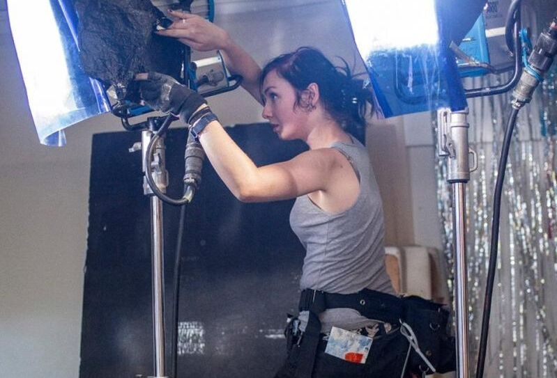 A gaffer adjusts a lighting set up on a film shoot.
