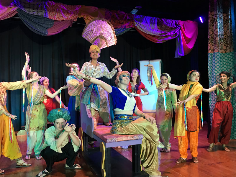 Student performers sing and dance on stage. 