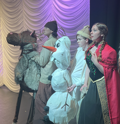 High school performers give high fives to elementary school audience members. 