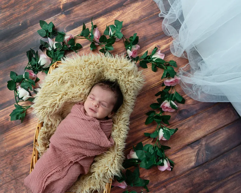 color photo of a baby newborn girl on a fur rug with roses around her head
