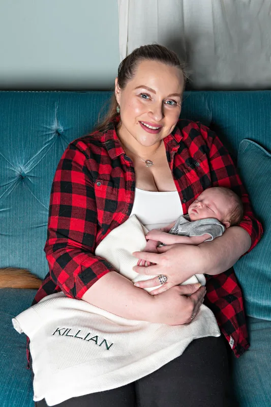 Color photo of a newborn baby boy being held by his mother. The photo is by Laura Pea Photography, a Long Island newborn and pet photographer. 