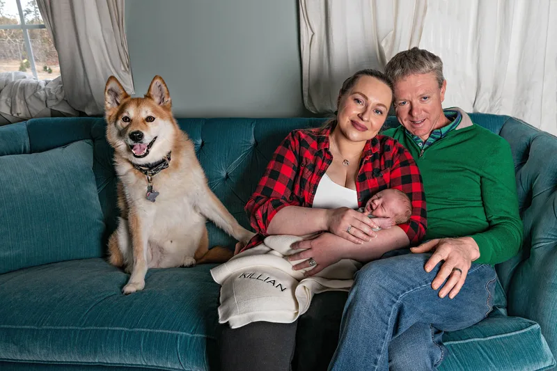Color photo of a newborn baby boy and his mom, dad and husky mix dog. The photo is by Laura Pea Photography, a Long Island newborn and pet photographer. 