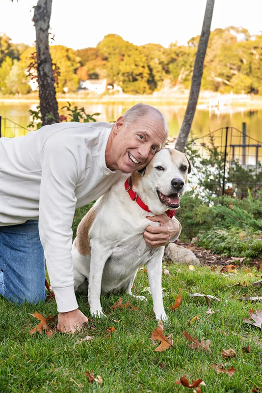 A photo of a brown and white hound mix dog and her owner, a white man. The photo is by Laura Pea Photography, a Long Island based pet photographer. 