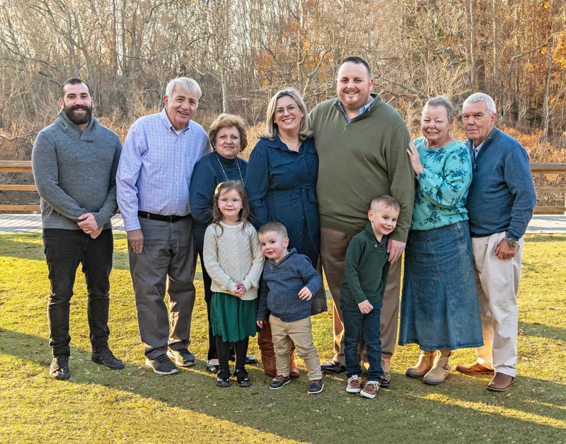 Color photo of a group extended family photo with mom, dad, both sets of grandparents, uncle and three kids.