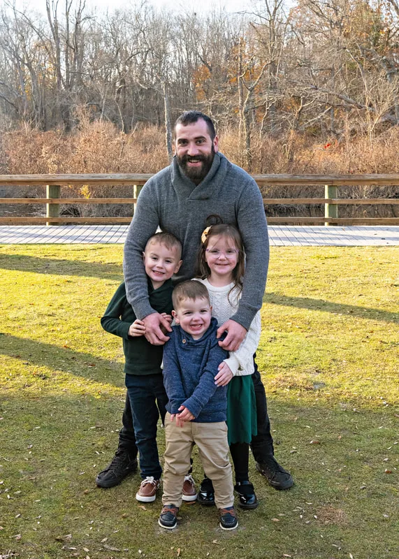 Color photo of an uncle posing with his niece and nephews.