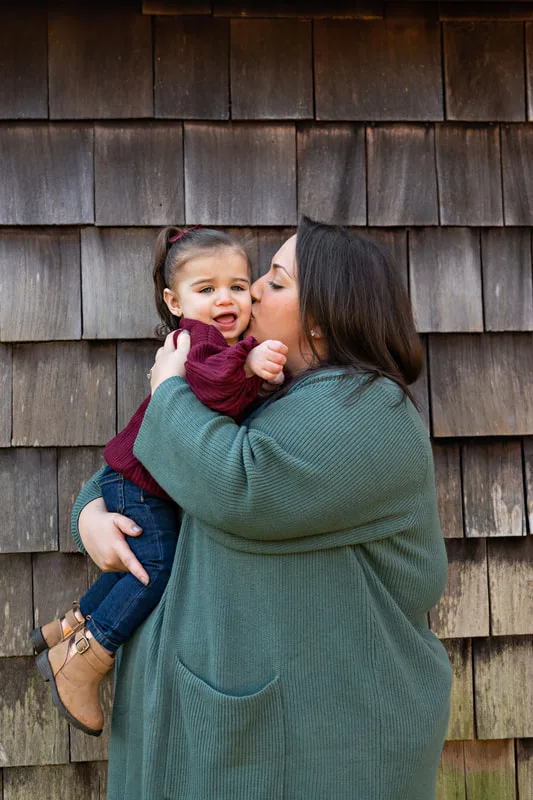 photo of a mom kissing her daughter on the cheek