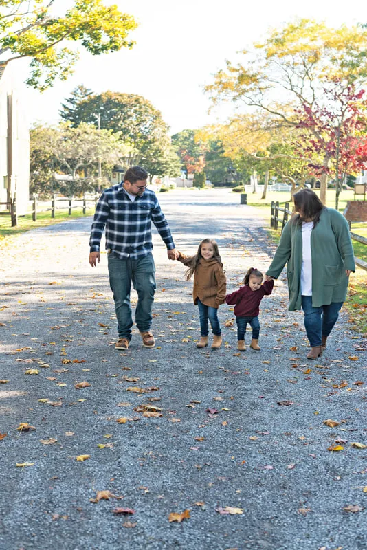 photo of a family of four walking hand in hand from behind