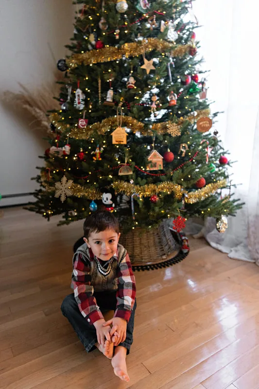 photo of a toddler boy in front of his Christmas tree