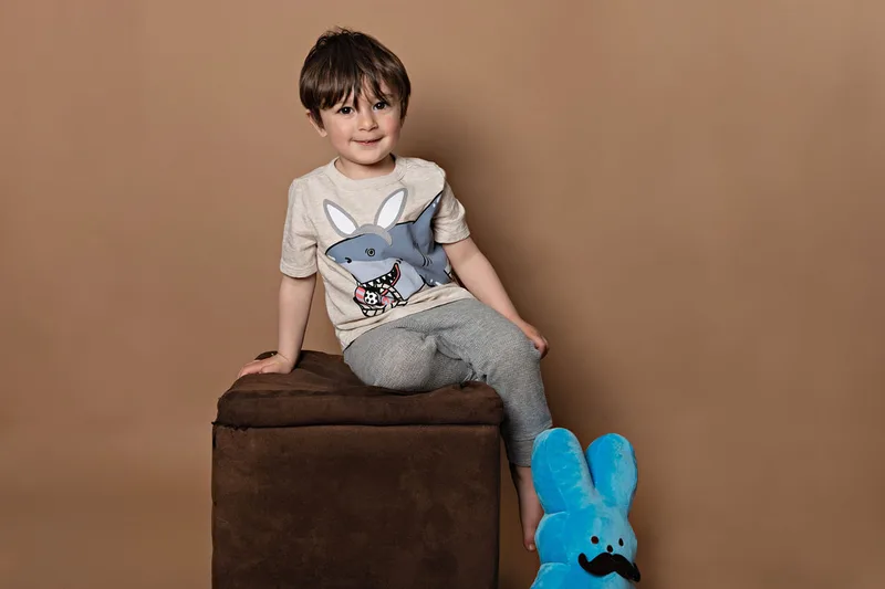 Toddler boy wearing a shirt with a shark dressed as an Easter bunny smiling at the camera