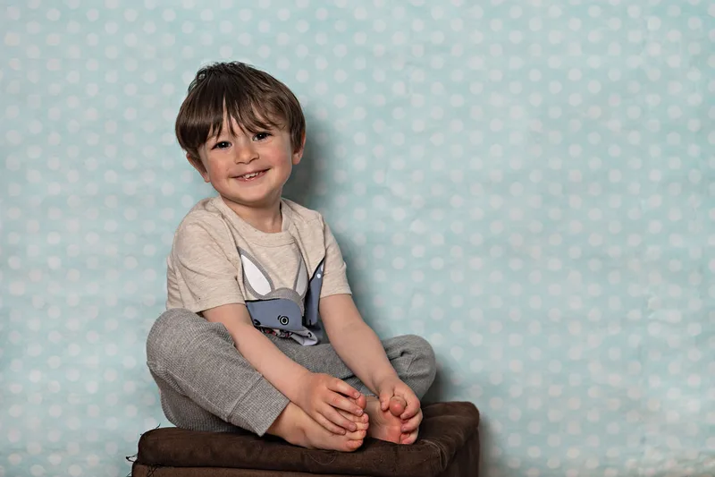 Toddler boy wearing a shirt with a shark dressed as an Easter bunny smiling at the camera