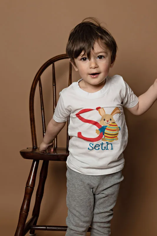 Toddler boy wearing a shirt with a letter S and a bunny looking at the camera