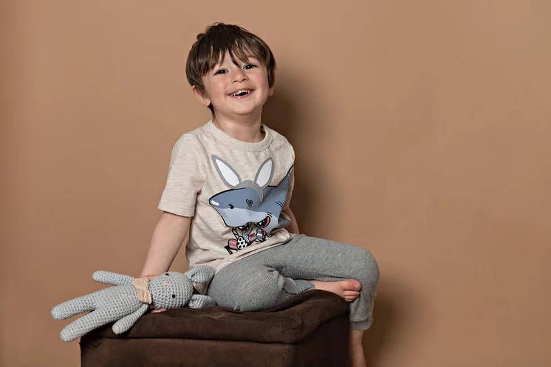 Toddler boy wearing a shirt with a shark dressed as an Easter bunny smiling at the camera