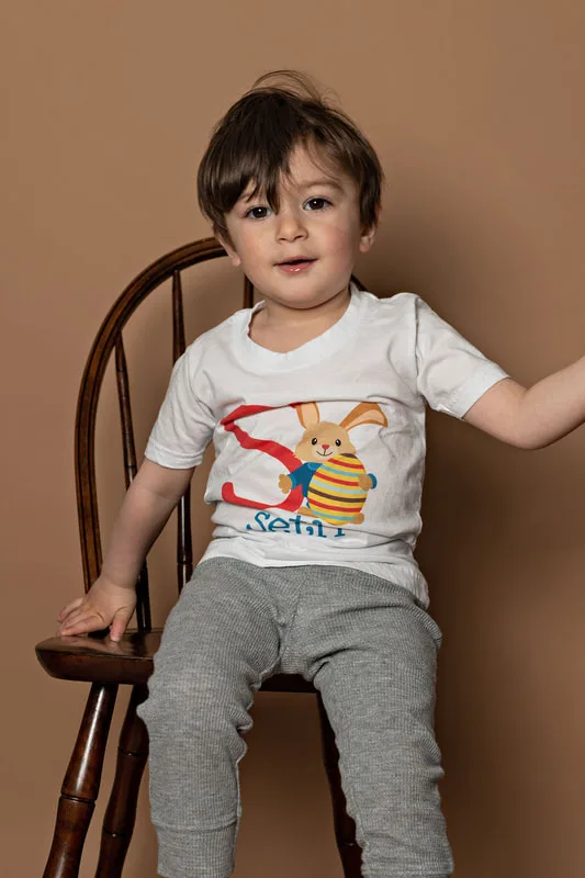 Toddler boy wearing a shirt with a letter S and a bunny looking at the camera