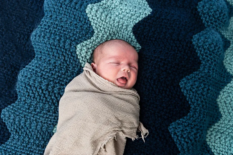 photo of a newborn baby boy from above on a homemade knit blanket