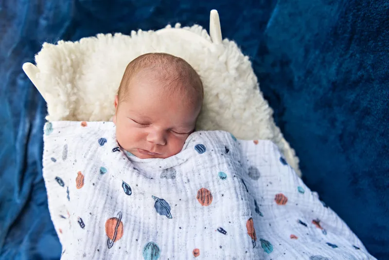 photo of a newborn baby boy from above with a space themed blanket