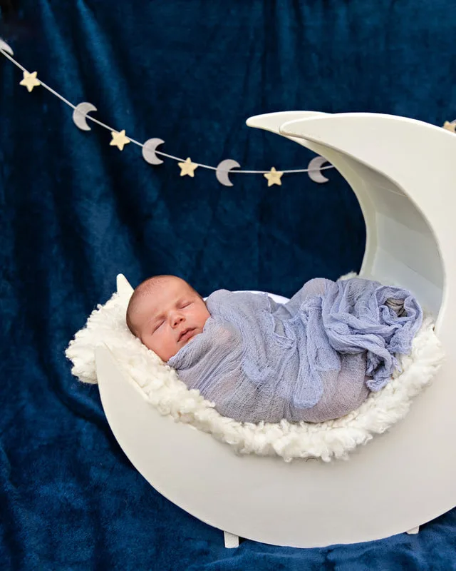 photo of a newborn baby boy from above in a white wooden moon prop