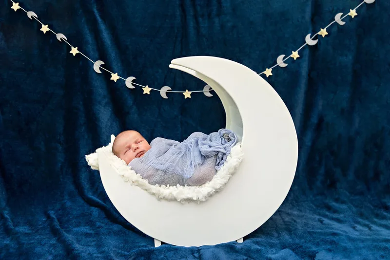 photo of a newborn baby boy in a white wooden moon prop