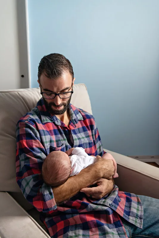 photo of a man who is a new father holding and looking down on his newborn baby boy