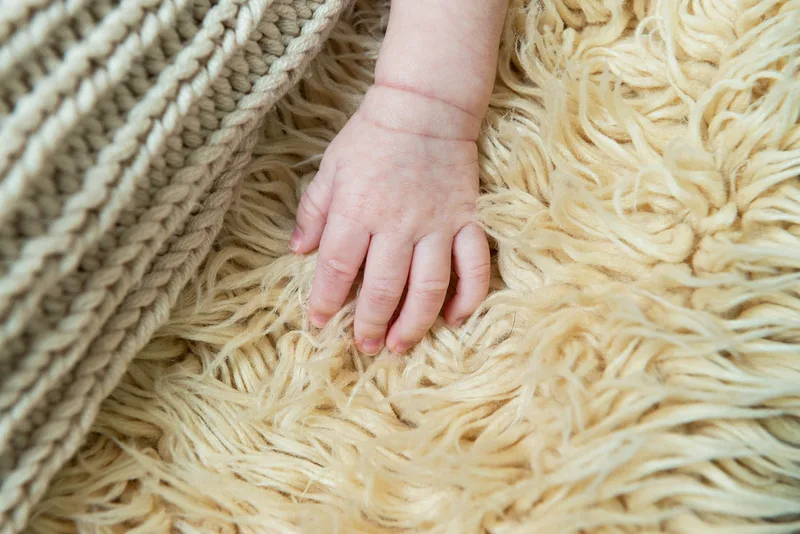 Color photo of a newborn baby photographed in a studio. The photo is a detail of his hand. The photo was taken by Laura Pea Photography, a Long Island based newborn photographer.