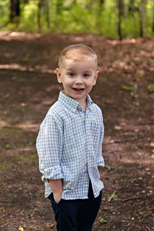 photo of a four year old boy smiling standing in a wooded park