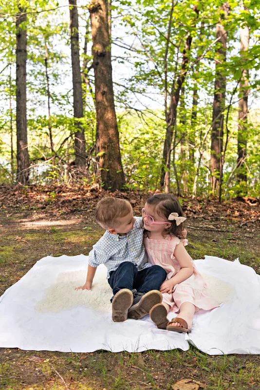 photo of two four year old twin brother and sister sitting on a blanket in a wooded park
