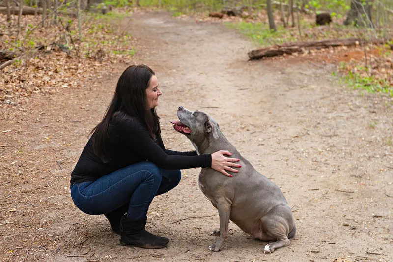 A color photo of a pit bull and her owner looking at each other lovingly