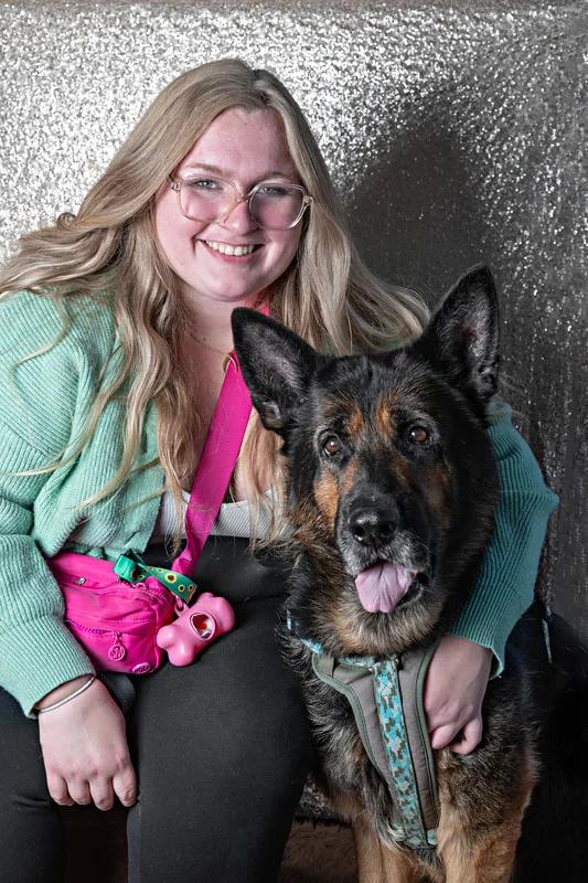Color photo of a German Shepherd dog and its owner against a  sequin background. The photo was taken by Laura Pea Photography, a pet photographer on Long Island.