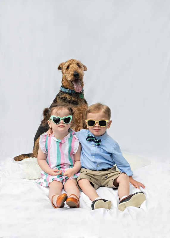 portrait of an airedale terrier dog with two toddler twins, a boy and a girl