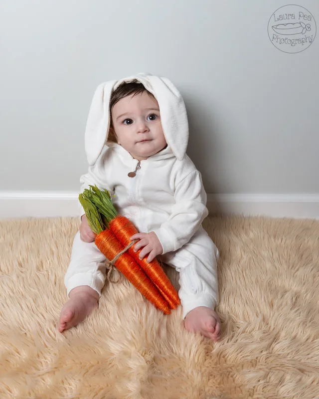 picture of baby boy's first easter photo session in an easter bunny costume holding carrots prop