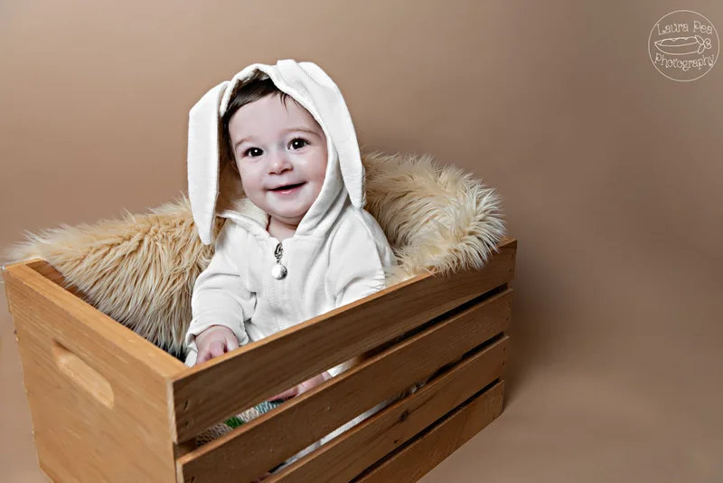 picture of baby boy's first easter photo session in an easter bunny costume smiling at the camera sitting in a wooden crate