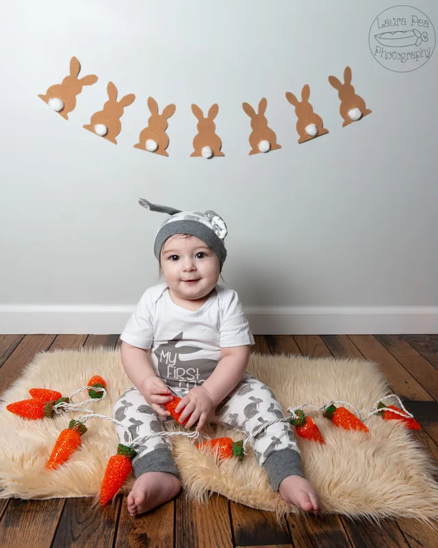 picture of baby boy's first easter photo session in an easter bunny costume holding carrot shaped lights