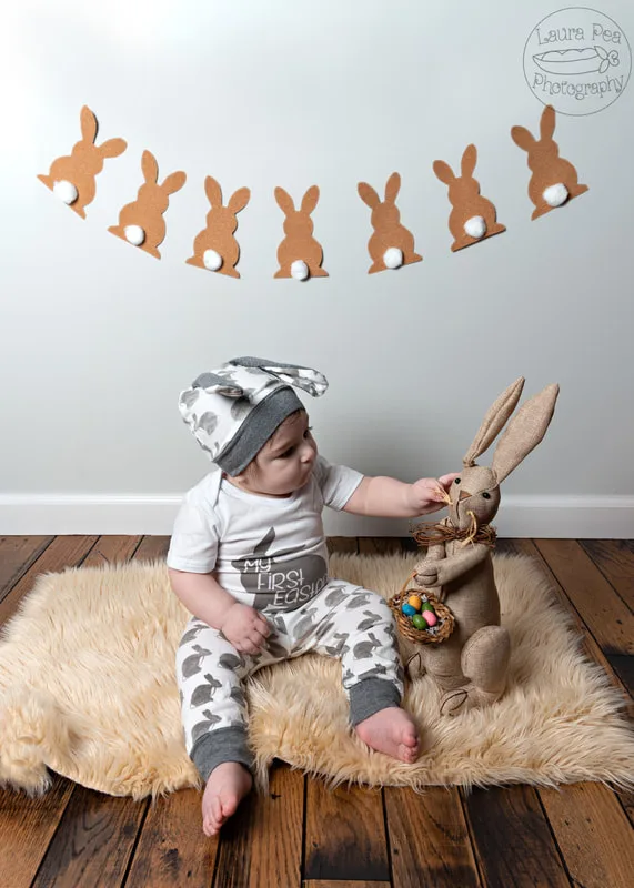 picture of baby boy's first easter photo session in an easter bunny costume looking at a rabbit prop