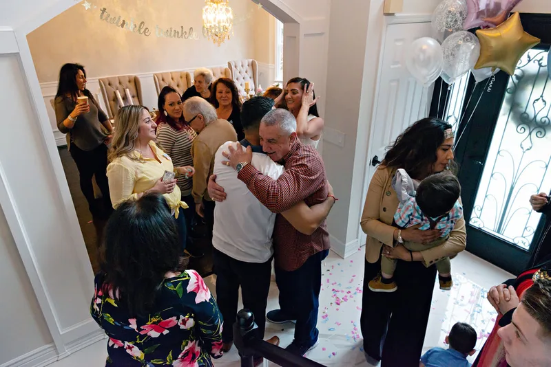 picture of family and friend party guests hugging and celebrating at a gender reveal party