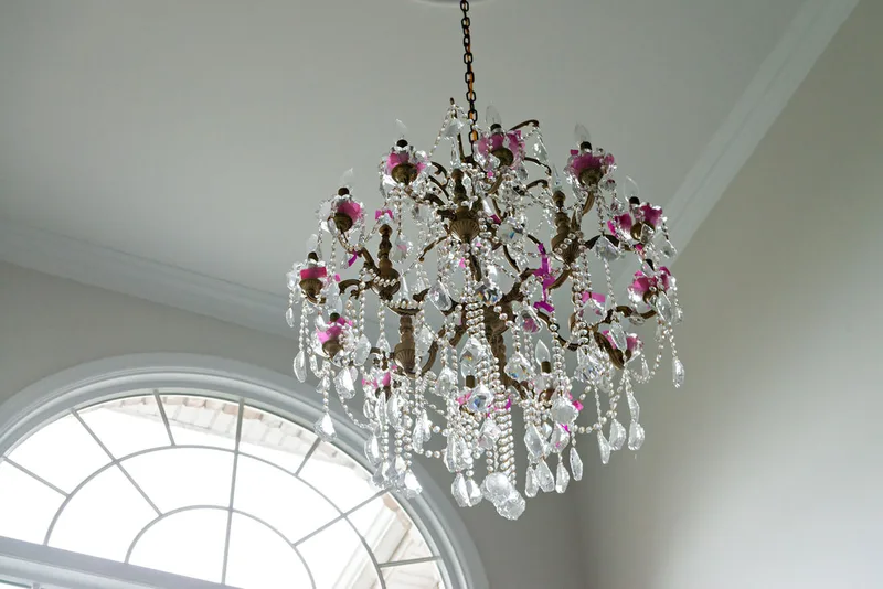 picture of a chandelier with pink confetti stuck in it at a gender reveal party