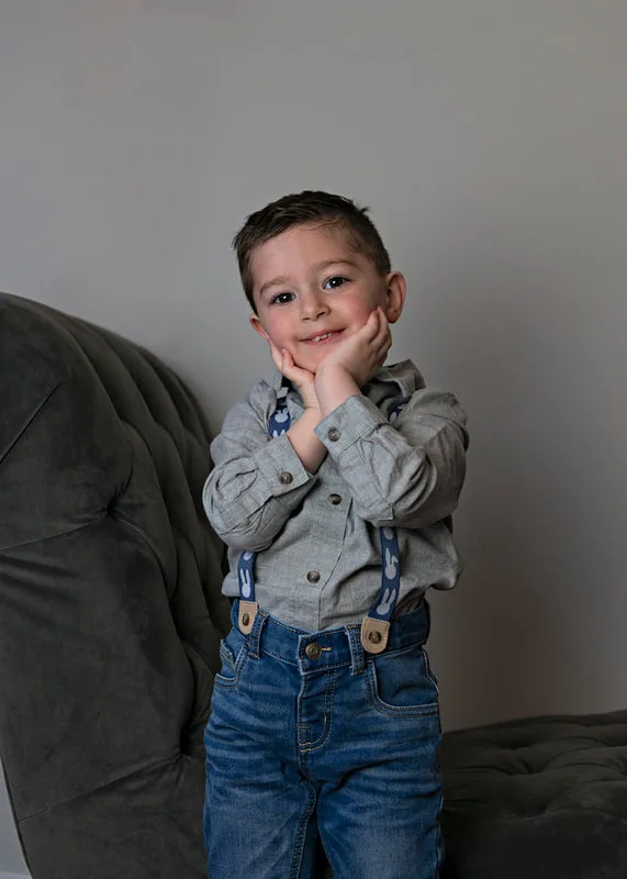 photo of a white toddler boy in an Easter outfit posing with his hands under his chin