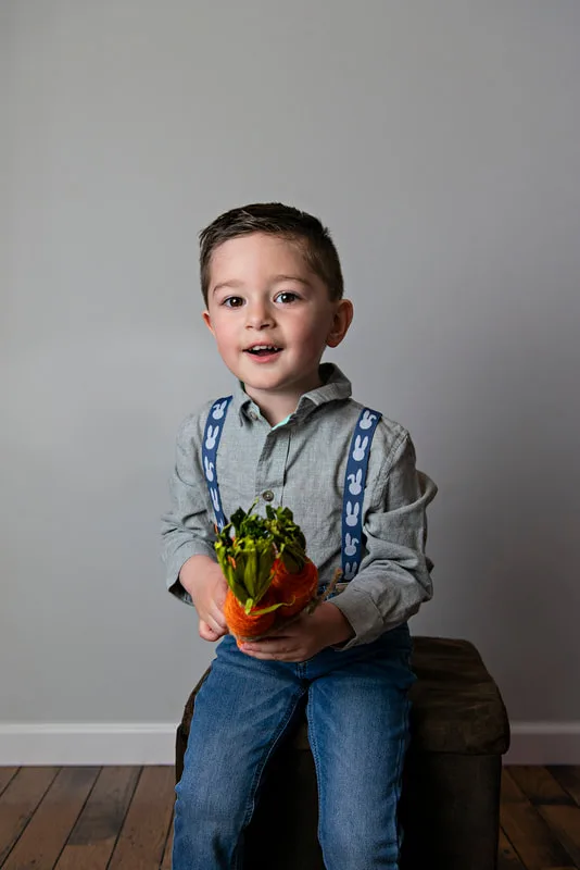 photo of a white toddler boy in an Easter outfit holding carrots