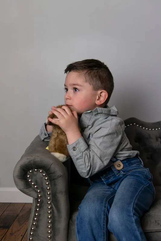 photo of a white toddler boy in an Easter outfit hugging a stuffed bunny rabbit