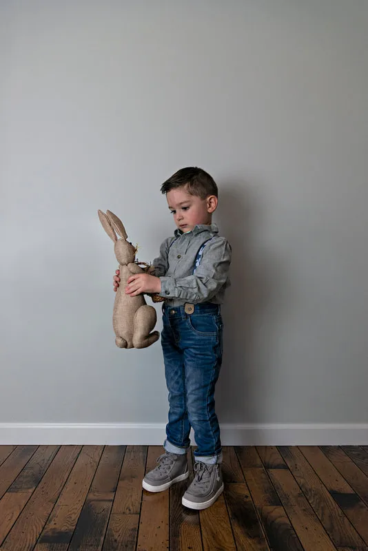 photo of a white toddler boy in an Easter outfit holding a bunny rabbit
