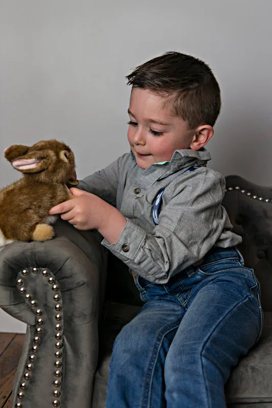 photo of a white  toddler boy in an Easter outfit looking down at a stuffed bunny rabbit