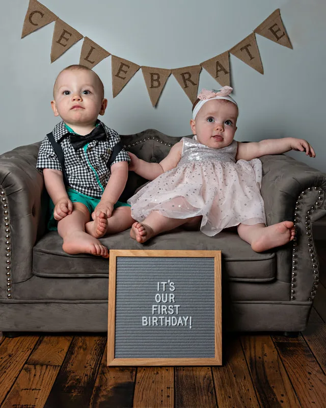 One year old twin boy and girl first birthday photos on gray couch