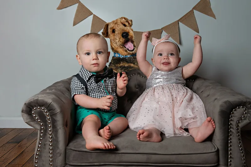 One year old twin boy and girl with their Airedale terrier dog for first birthday photos 
