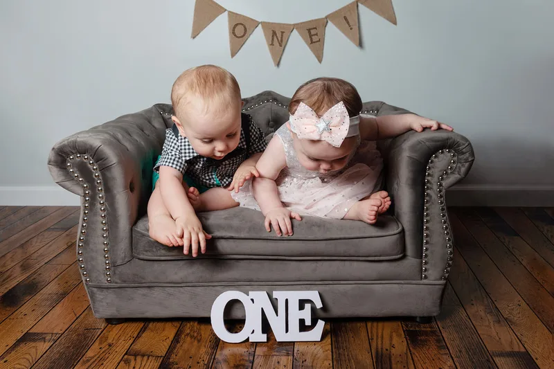 One year old twin boy and girl first birthday photos looking down at wooden one sign